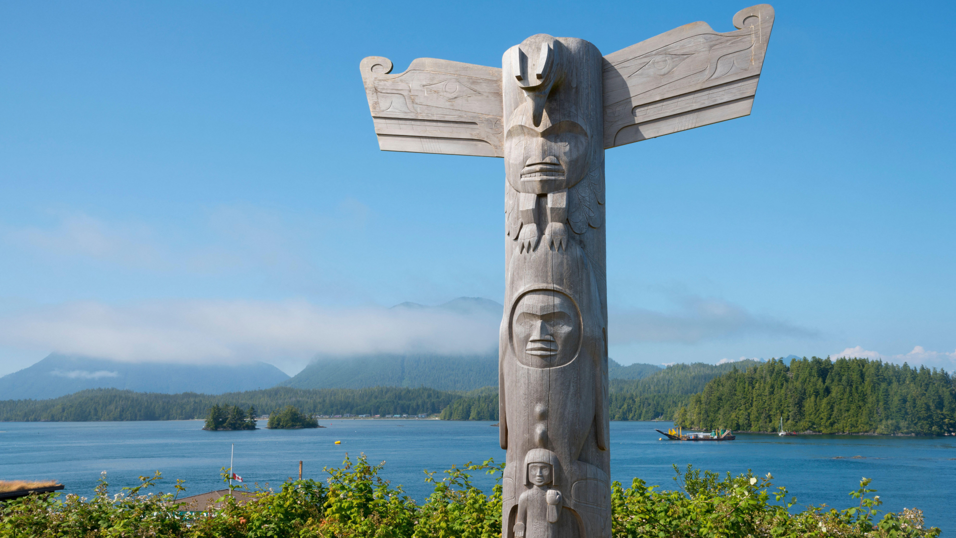 a wood totem pole in front of a lake in British Columbia, Canada